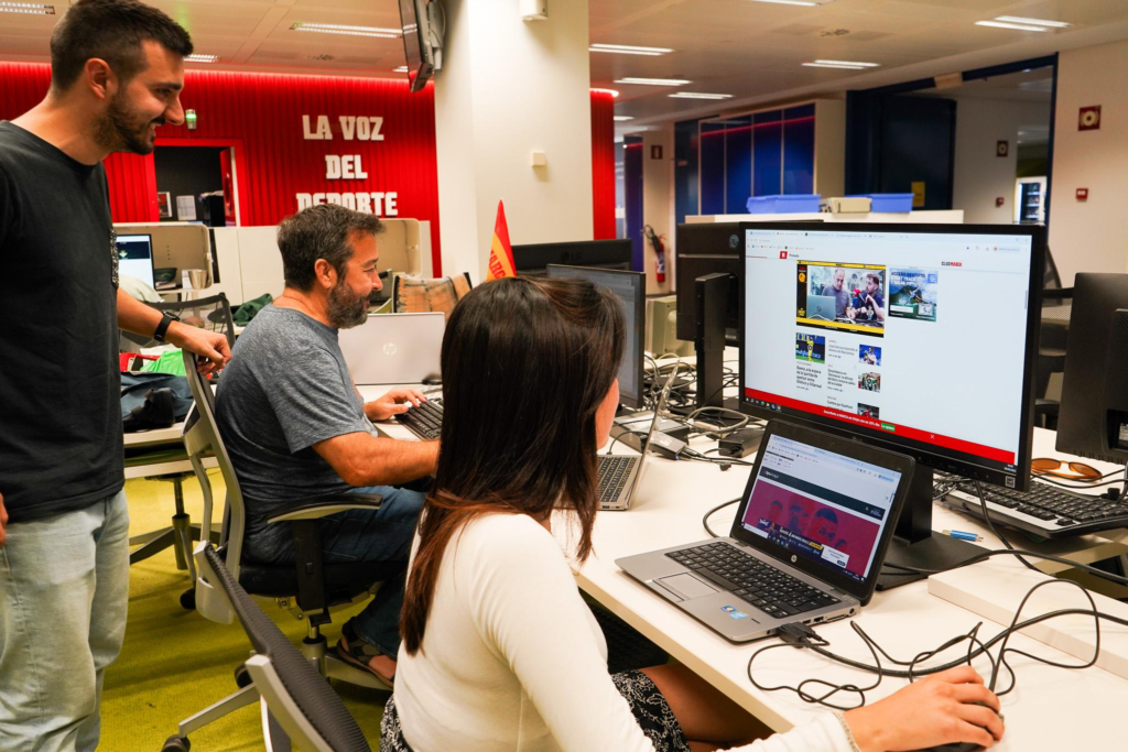 A football content creator recording a match analysis video in a modern studio, with tactical graphics and match highlights displayed on multiple monitors.
